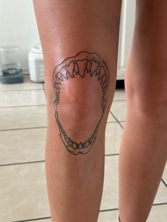 a woman's leg with a tattoo on it that has a mouth and teeth