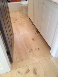 a bathroom with wood floors and white cabinets