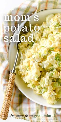 a white bowl filled with potato salad on top of a checkered cloth next to a fork