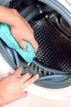 a person is cleaning the front of a washing machine with a blue cloth on it