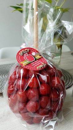 a plastic bag filled with red fruit sitting on top of a table next to a vase