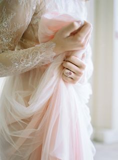 a woman wearing a pink dress and holding onto her wedding ring