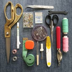 sewing supplies laid out on a table with scissors, thread, tape and spools