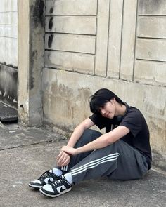 a person sitting on the ground next to a building