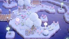 a snow covered park with lights and flowers on the ground in front of it, surrounded by water