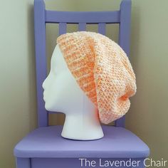 a knitted hat sitting on top of a purple chair next to a white mannequin head