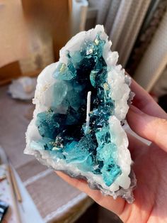 a person holding up a piece of blue and white rock with crystals on the inside