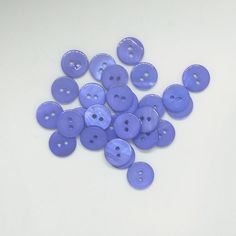 a pile of purple buttons sitting on top of a white table