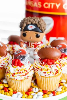 some cupcakes with football decorations on them and candy in the shape of helmets