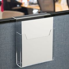 an office cubicle with a folder attached to the wall and a chair in the background