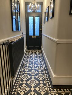 a hallway with black and white tile flooring and chandelier hanging from the ceiling