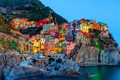 the colorful village is perched on top of a cliff by the ocean at night time