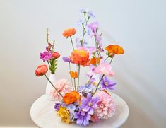 a white vase filled with colorful flowers on top of a table