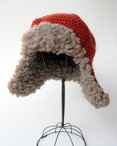 a red and white hat on top of a metal stand with a wire rack underneath it