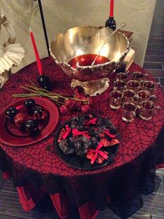 a red table topped with plates and bowls filled with food next to candle holders on top of a wooden table