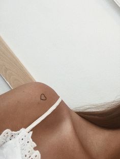 a woman with a small heart tattoo on her shoulder