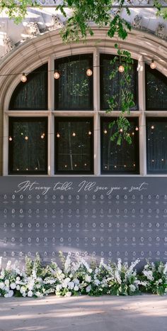 a sign that says happy new year next to some flowers and greenery in front of an arched window