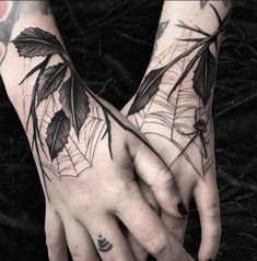 two hands with tattoos on them holding each other's fingers and one hand is covered in leaves