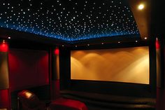 a home theater with stars on the ceiling and red chairs in front of the screen