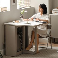 a woman sitting at a desk in front of a window