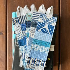 several pieces of blue and white fabric sitting on top of a wooden table next to a book