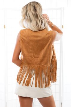 Step into bohemian chic with the Fleetwood Camel Suede Embroidered Fringe Vest! This trendy vest features an open front, sleeveless design, and is crafted from luxurious faux suede for a stylish and comfortable fit. The solid camel color is adorned with intricate ivory floral embroidery on the front, while fringe accents on the hems add a playful touch. With its cropped styling, this vest is the perfect statement piece to elevate any outfit with a touch of free-spirited flair! Features: Luxuriou Hippie Sleeveless Vest For Spring, Bohemian Sleeveless Tops For Fall, Hippie Style Vest For Fall Festival, Bohemian Brown Vest Top, Bohemian Fringe Vest For Festivals, Bohemian Vest Tops For Fall, Sleeveless Vest For Fall Festival, Sleeveless Fall Festival Top, Brown Fringe Vest For Festival