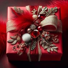 a red present wrapped in gold foil and surrounded by feathers, beads, and ornaments