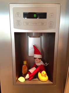 an elf doll sitting in the middle of a refrigerator with a rubber duck next to it