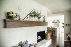 a living room filled with furniture and a fire place under a mantle covered in plants