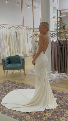 a woman standing in front of a rack of wedding dresses at a bridal shop