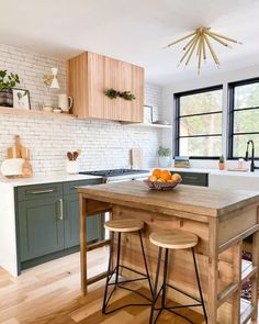 a kitchen with green cabinets and wooden counter tops, along with stools that match the hardwood flooring