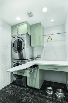 a washer and dryer in a small room with white tile flooring, green cabinets and stainless steel appliances