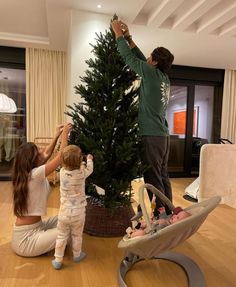 a man and two children decorating a christmas tree