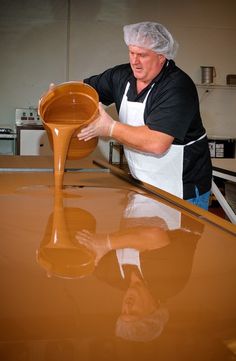 a man pouring liquid into a pan on top of a counter