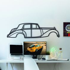 a computer desk with a laptop and monitor on it, next to a wall mounted race car