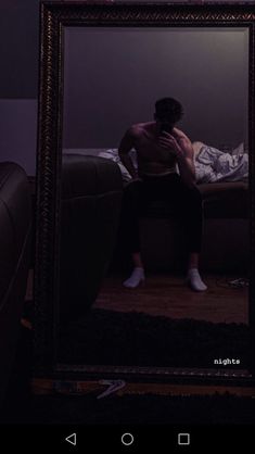 a man sitting on a couch in front of a mirror