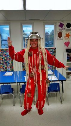 a person in a red costume standing next to a table with chairs and desks