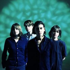 four people standing in front of a green background