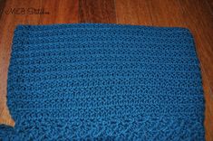 a blue crocheted blanket laying on top of a wooden floor