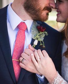 a man in a suit and tie is holding a woman's hand while they both hold their wedding rings