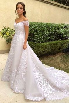 a woman in a white wedding dress standing outside