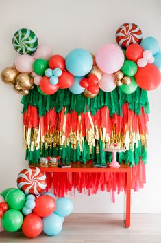 a table topped with balloons and streamers next to a wall filled with candy canes