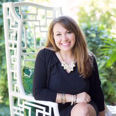 a woman sitting in a white chair with her arms crossed and smiling at the camera