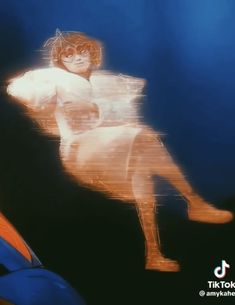 a blurry image of a naked woman sitting on a chair in front of a blue background