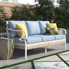 a blue couch sitting on top of a patio next to a planter and potted tree