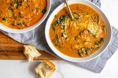 two bowls of soup with bread on the side