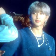 a young man in a blue shirt and necklace