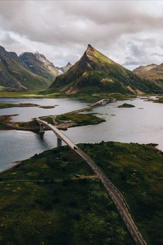 an aerial view of a road going through some water and mountains in the distance,