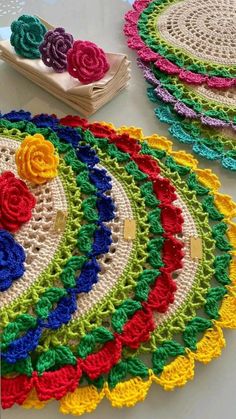 crocheted placemats with flowers on them sitting on a white table top