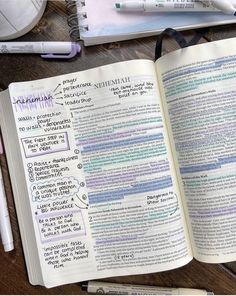 an open book with writing on it next to some pens and other office supplies in the background